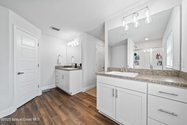 bathroom with vanity, hardwood / wood-style floors, and a shower with door