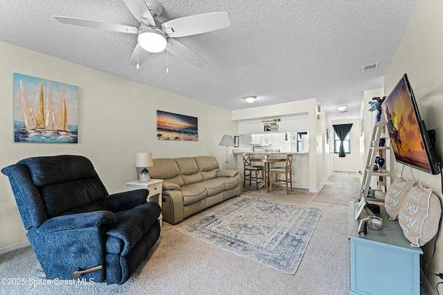 carpeted living room with ceiling fan and a textured ceiling