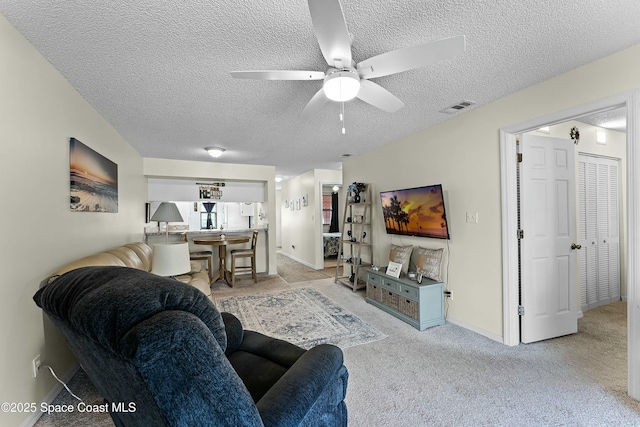 living room featuring light carpet, ceiling fan, and a textured ceiling