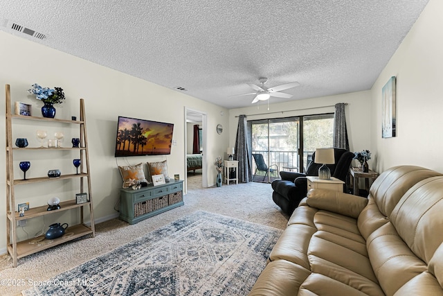 living room featuring ceiling fan, carpet flooring, and a textured ceiling