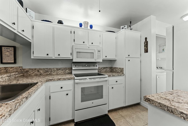 kitchen featuring light tile patterned floors, white appliances, washer / dryer, and white cabinets