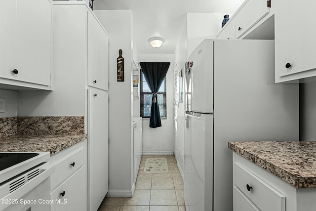 kitchen with white refrigerator, light tile patterned flooring, and white cabinets