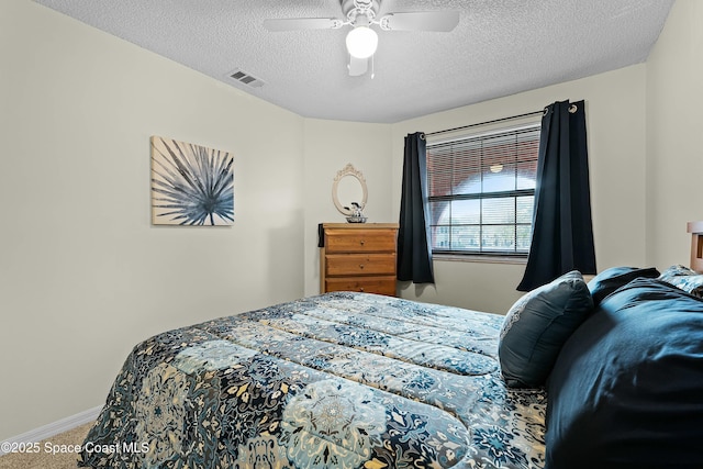 bedroom with ceiling fan, carpet, and a textured ceiling