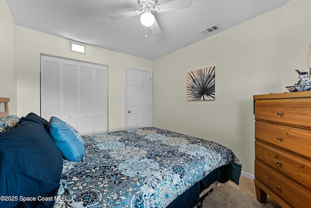 carpeted bedroom with ceiling fan, a closet, and a textured ceiling