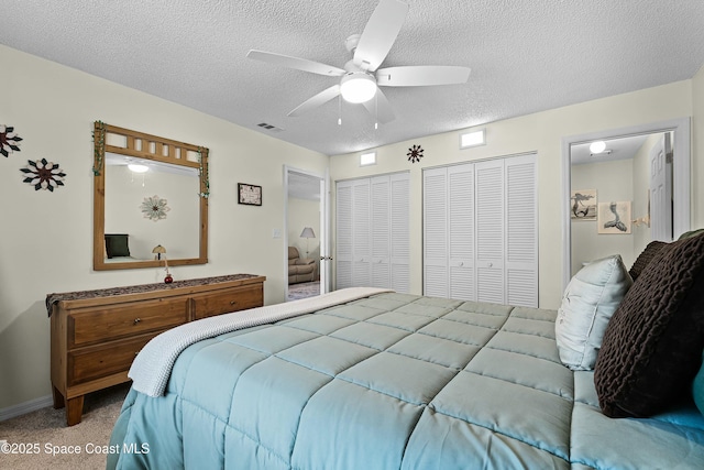 bedroom with multiple closets, ceiling fan, a textured ceiling, and carpet flooring