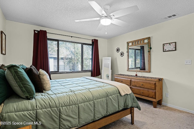 carpeted bedroom featuring ceiling fan and a textured ceiling