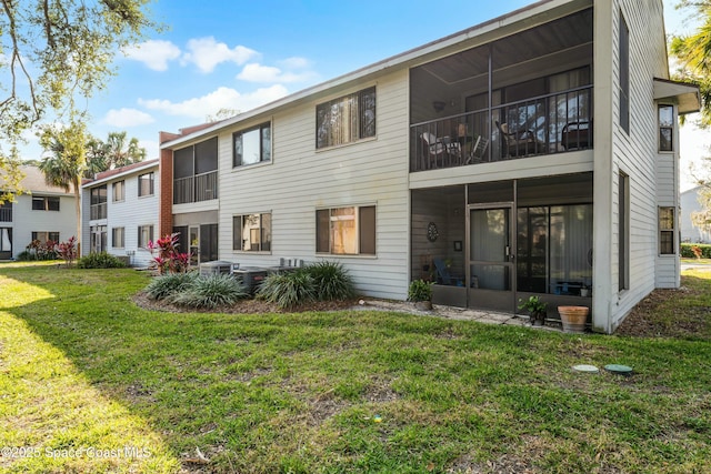 rear view of property featuring a sunroom and a yard