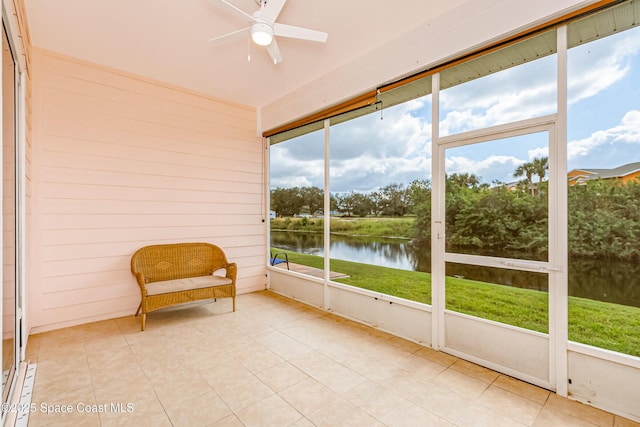 unfurnished sunroom featuring ceiling fan and a water view