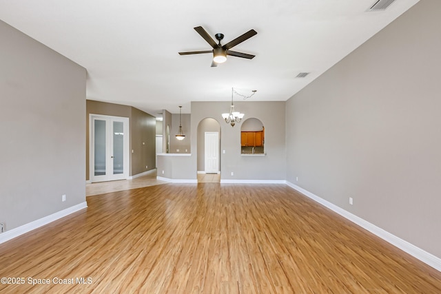 unfurnished living room featuring ceiling fan with notable chandelier and light hardwood / wood-style floors