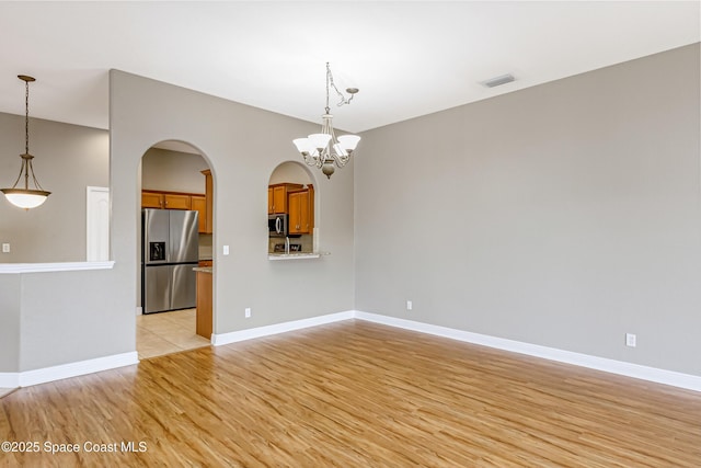 empty room with light hardwood / wood-style floors and a chandelier