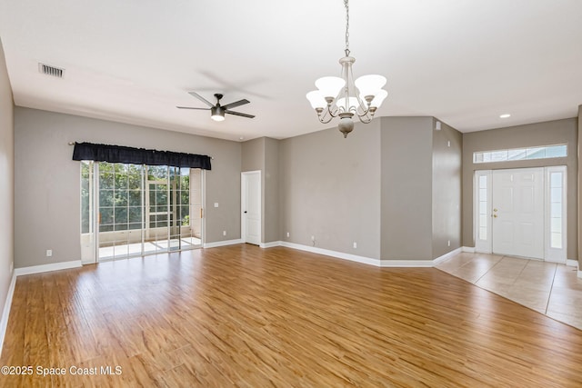 spare room with ceiling fan with notable chandelier and light hardwood / wood-style floors