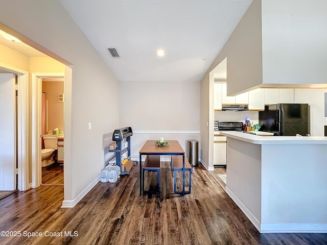 kitchen with white cabinetry, dark hardwood / wood-style floors, extractor fan, and black appliances