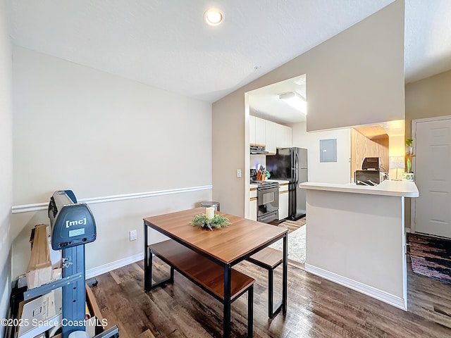 dining room featuring vaulted ceiling, dark hardwood / wood-style floors, and electric panel