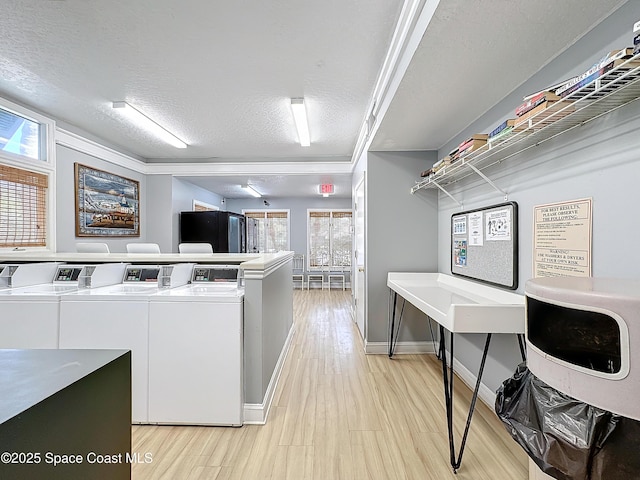 laundry area with washing machine and clothes dryer, light hardwood / wood-style flooring, and a textured ceiling