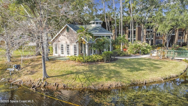 rear view of house with a water view and a yard