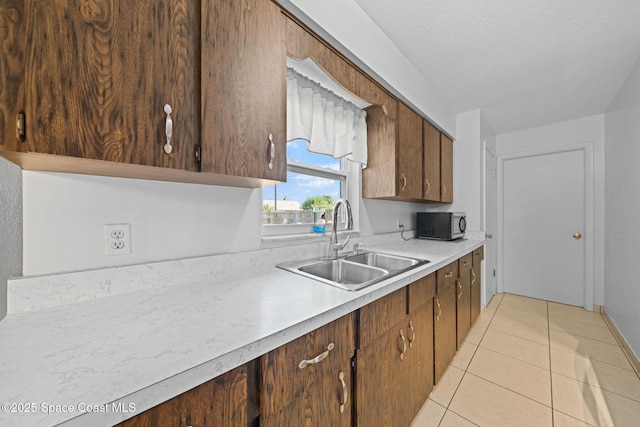 kitchen with light countertops, light tile patterned flooring, and a sink