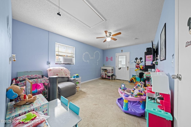 recreation room featuring a textured ceiling, cooling unit, baseboards, carpet, and attic access