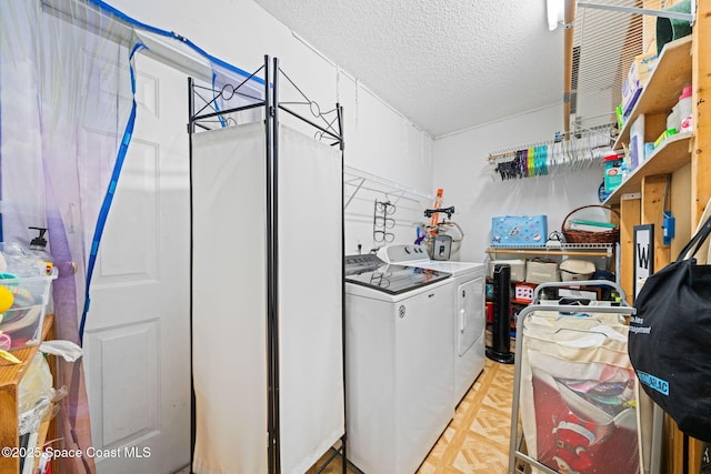 washroom with laundry area, a textured ceiling, and washing machine and clothes dryer