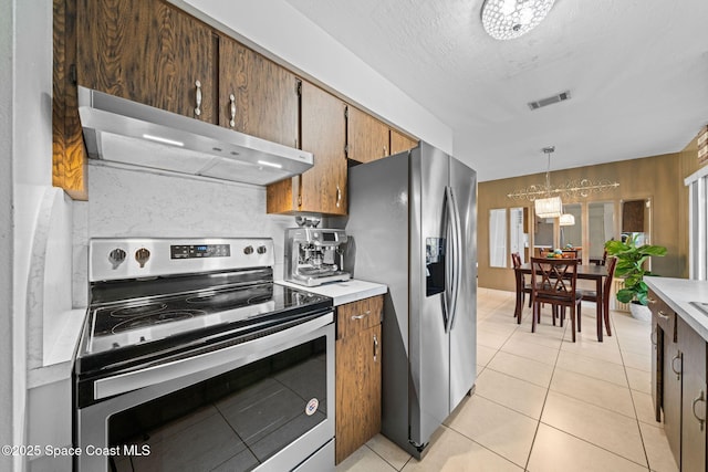 kitchen with stainless steel appliances, light countertops, visible vents, and under cabinet range hood