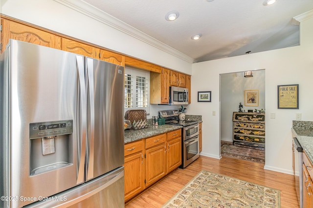 kitchen featuring crown molding, stainless steel appliances, light hardwood / wood-style floors, and dark stone counters