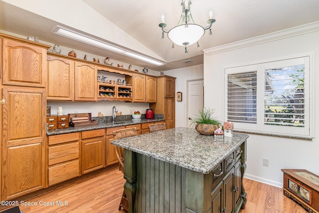 kitchen featuring lofted ceiling, a center island, hanging light fixtures, dark stone countertops, and light hardwood / wood-style floors