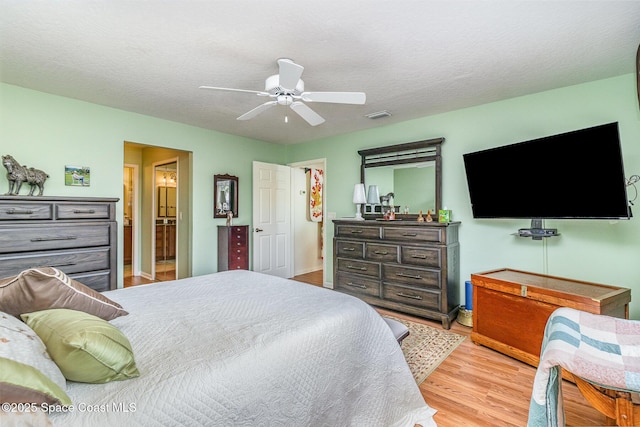 bedroom featuring ceiling fan, light hardwood / wood-style flooring, and a textured ceiling