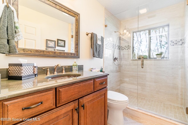 bathroom featuring tile patterned flooring, vanity, a shower with shower door, and toilet