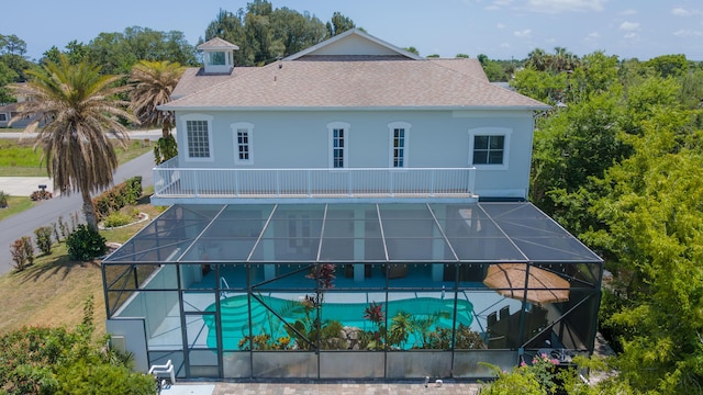 back of property featuring a balcony, a patio, and glass enclosure