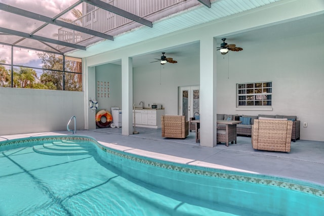 view of swimming pool featuring exterior kitchen, a lanai, an outdoor hangout area, ceiling fan, and a patio area