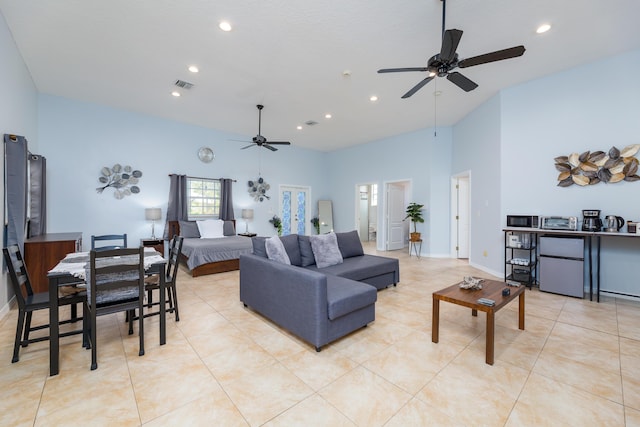 tiled living room with ceiling fan and a high ceiling