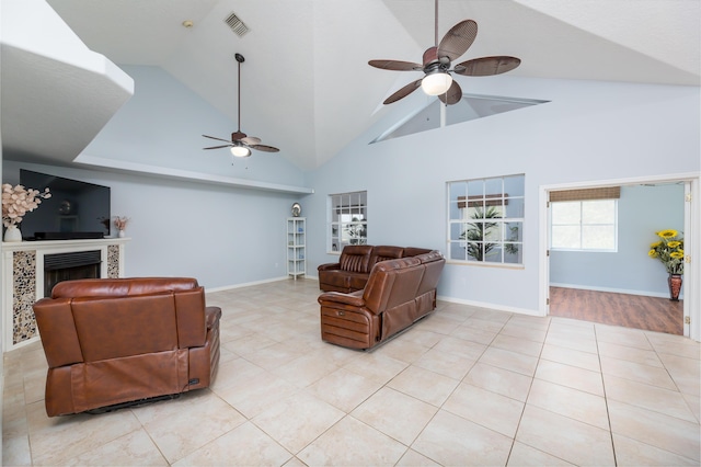 living room with light tile patterned floors, high vaulted ceiling, a tile fireplace, and ceiling fan