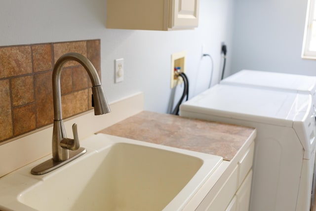 laundry area with sink, washing machine and dryer, and cabinets