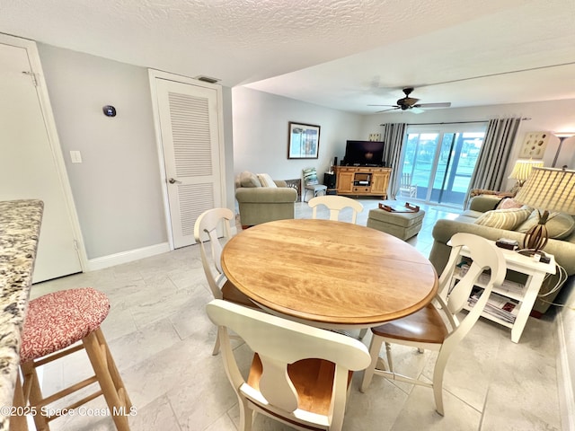 dining area featuring ceiling fan and a textured ceiling