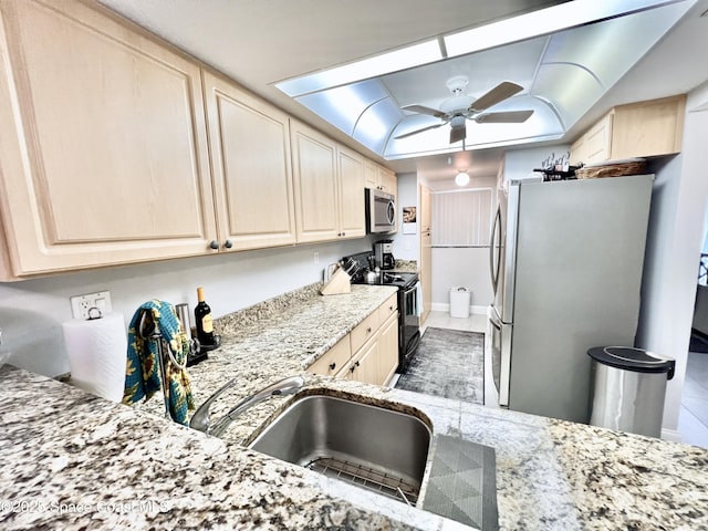 kitchen with stainless steel appliances, light stone countertops, light brown cabinets, and ceiling fan