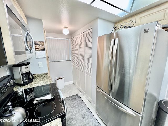 kitchen featuring light stone countertops, a skylight, and stainless steel appliances