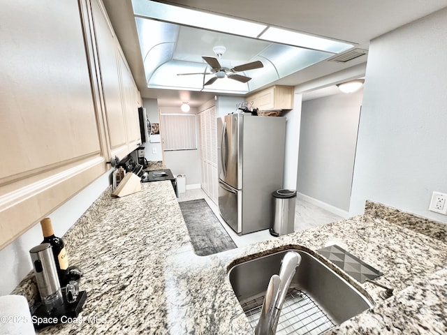 kitchen featuring sink, light stone countertops, ceiling fan, and appliances with stainless steel finishes