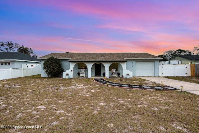 ranch-style house with a garage, a lawn, and covered porch