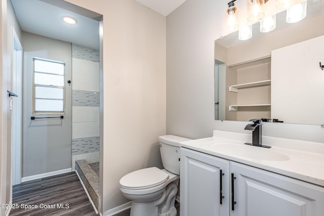 bathroom with vanity, wood-type flooring, toilet, and tiled shower