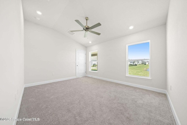 spare room featuring light carpet, vaulted ceiling, and ceiling fan