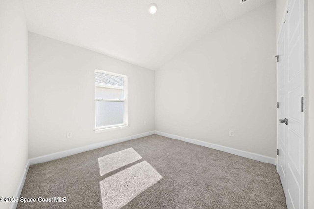 carpeted empty room with lofted ceiling