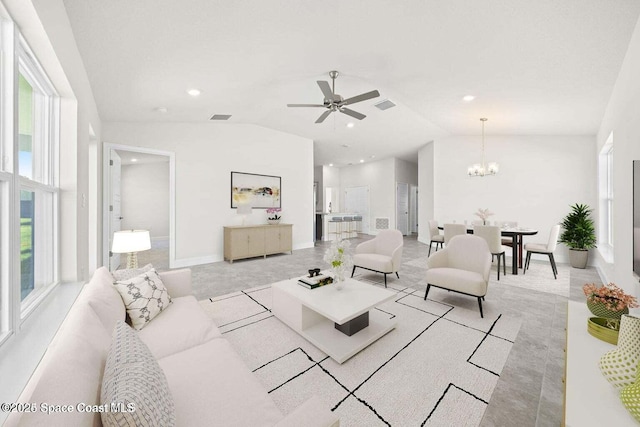 carpeted living room with ceiling fan with notable chandelier and vaulted ceiling