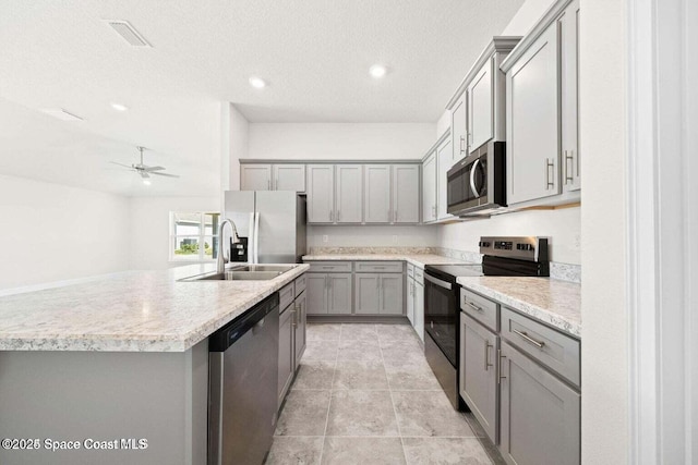 kitchen with sink, gray cabinets, a kitchen island with sink, stainless steel appliances, and a textured ceiling