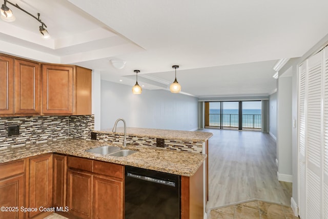 kitchen with sink, light stone counters, hanging light fixtures, black dishwasher, and backsplash