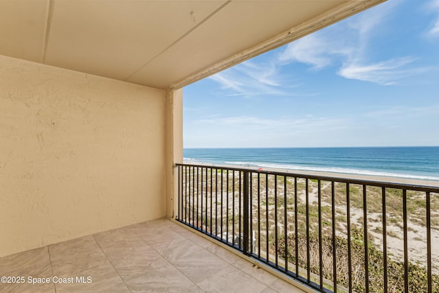 balcony with a water view and a view of the beach