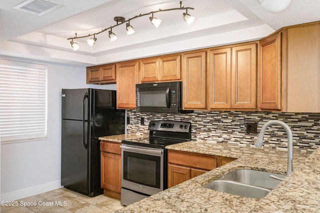 kitchen featuring light stone countertops, a tray ceiling, black appliances, and sink