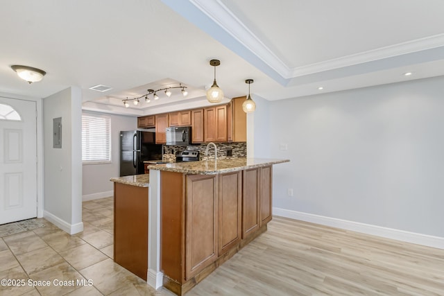 kitchen with pendant lighting, light stone counters, black appliances, a raised ceiling, and kitchen peninsula