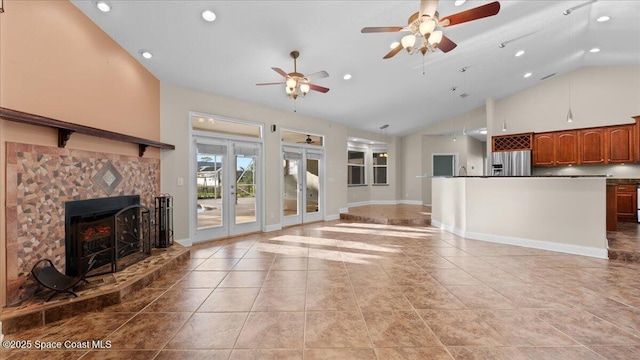 unfurnished living room with light tile patterned floors, baseboards, a tiled fireplace, high vaulted ceiling, and recessed lighting