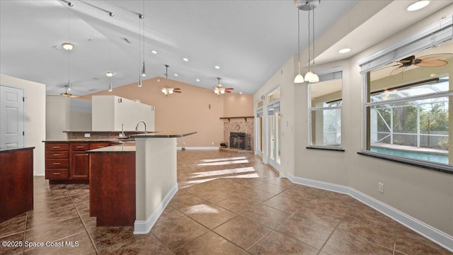 kitchen featuring dark countertops, lofted ceiling, open floor plan, a sink, and ceiling fan