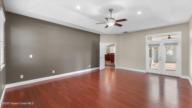 unfurnished room featuring baseboards, a tray ceiling, and wood finished floors