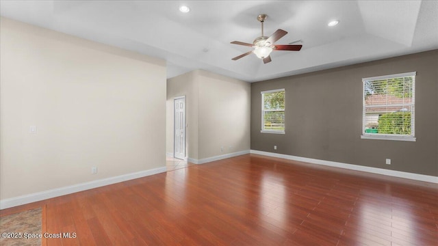 empty room with baseboards, a raised ceiling, ceiling fan, wood-type flooring, and recessed lighting